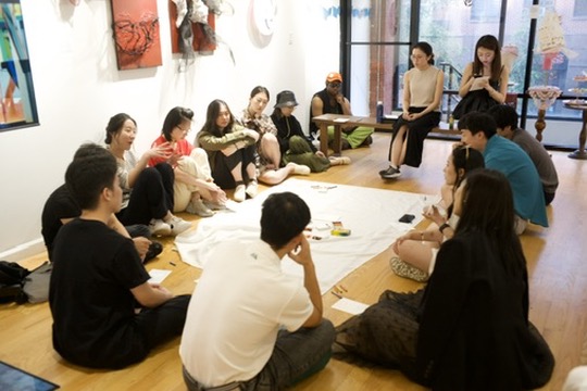 Sit-circle discussion with shared paper canvas in a gallery