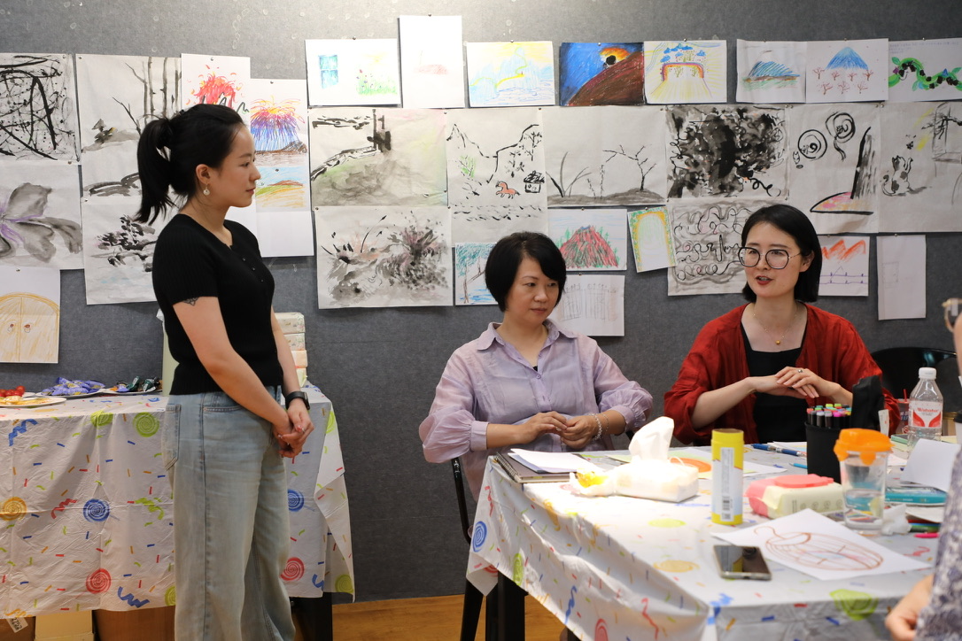 Discussion in front of student ink paintings on the wall