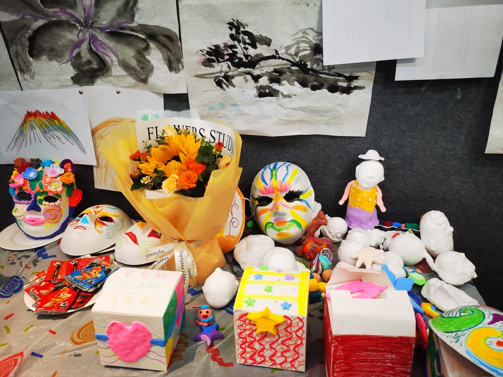 Display of finished masks, clay sculptures, and ink paintings from a multi-day workshop